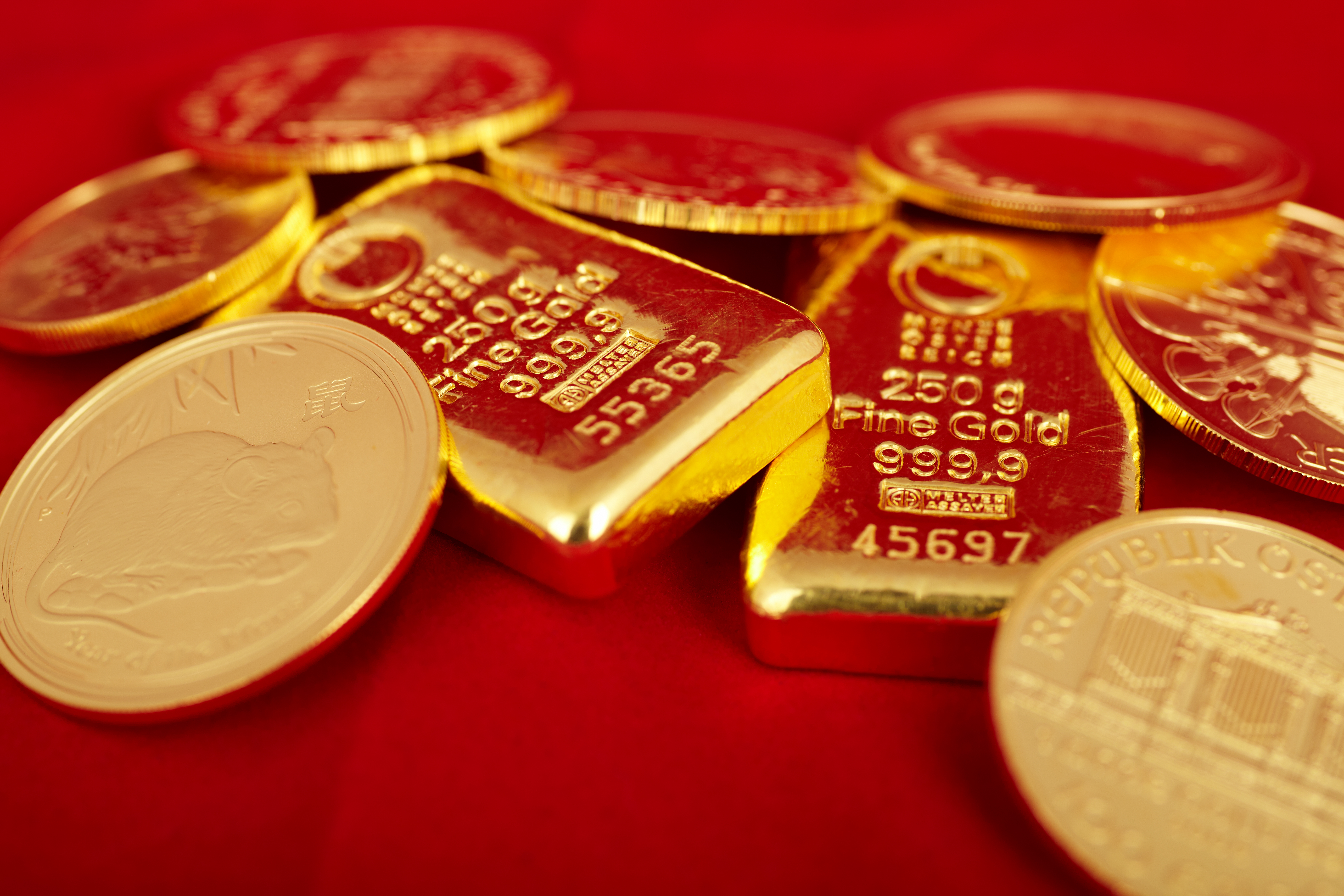 Goldmünzen und Goldbarren auf rotem Samtstoff