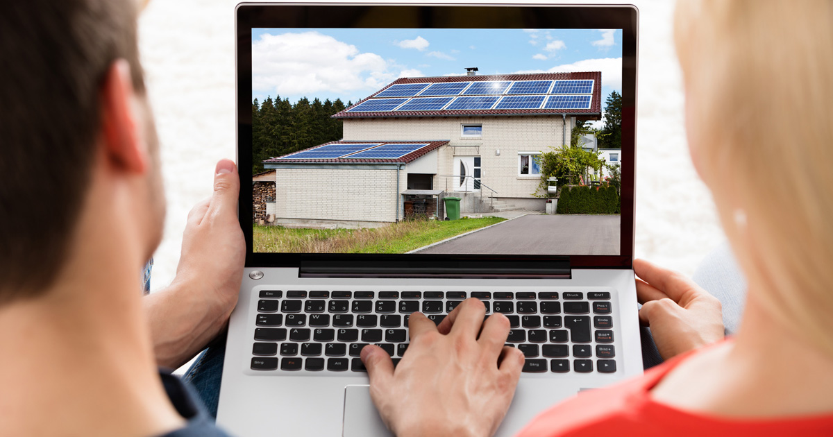 Ein Mann und eine Frau vor einem Laptop mit Foto eines Hauses mit Solardach
