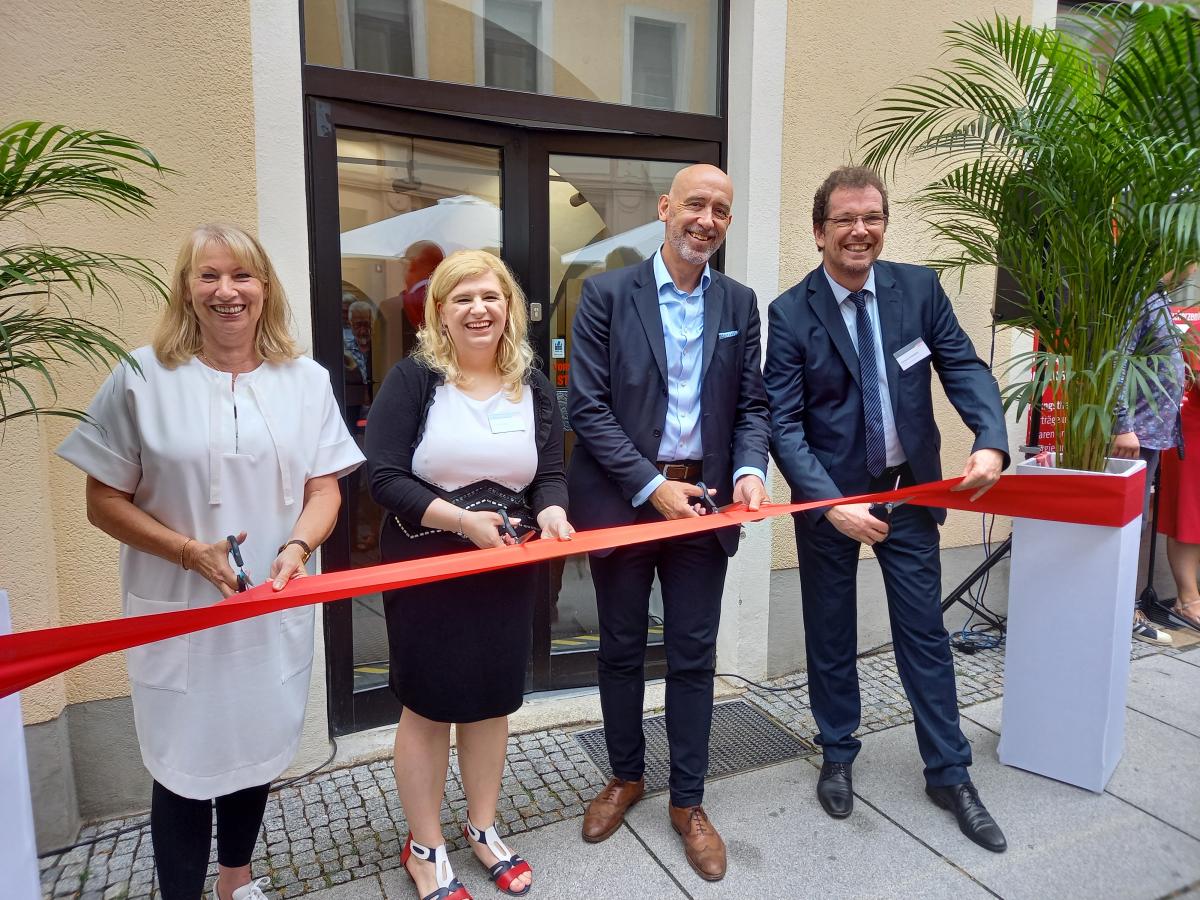 Feierliche Eröffnung. Anwesende zerschneiden ein rotes Band