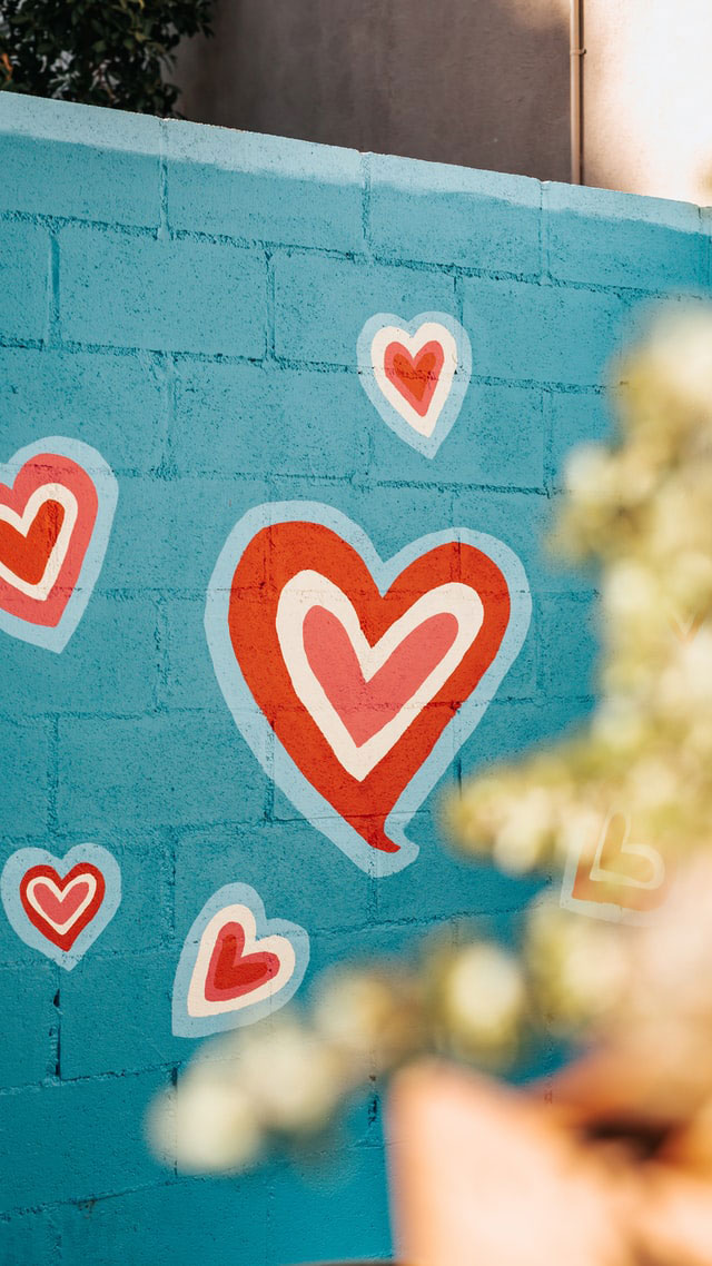 Online-Dating: Auf eine blau gestrichene Steinmauer sind rote Herzen gemalt
