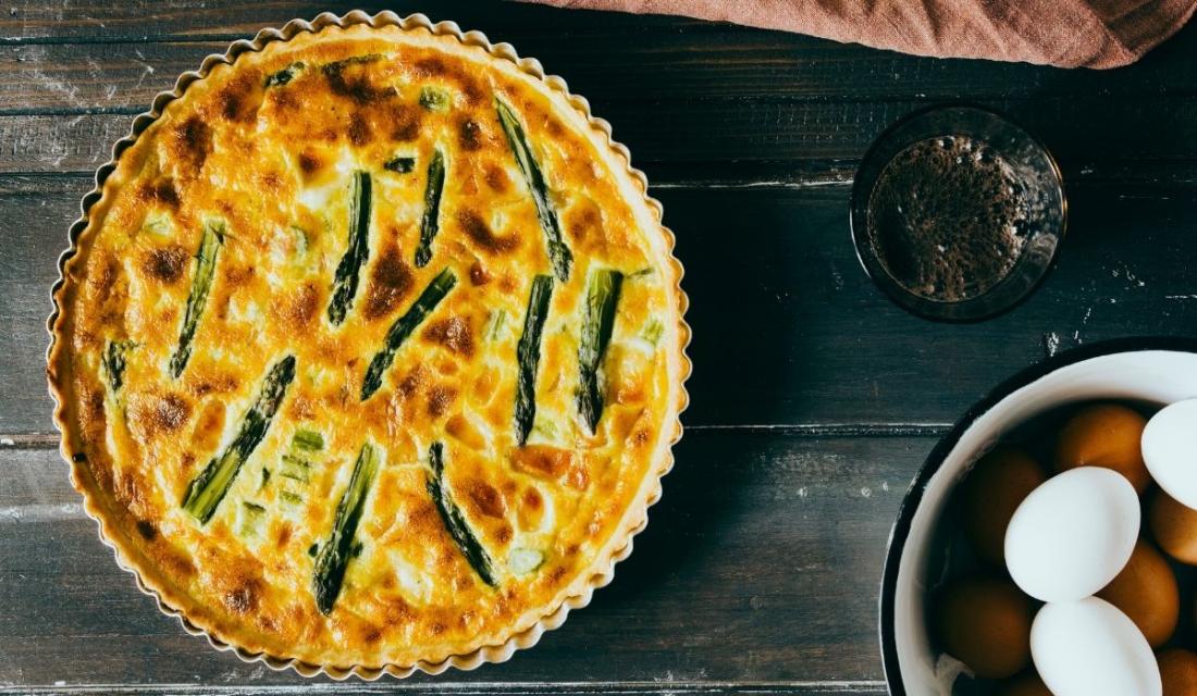 Eine Spargelquiche, daneben liegen Eier