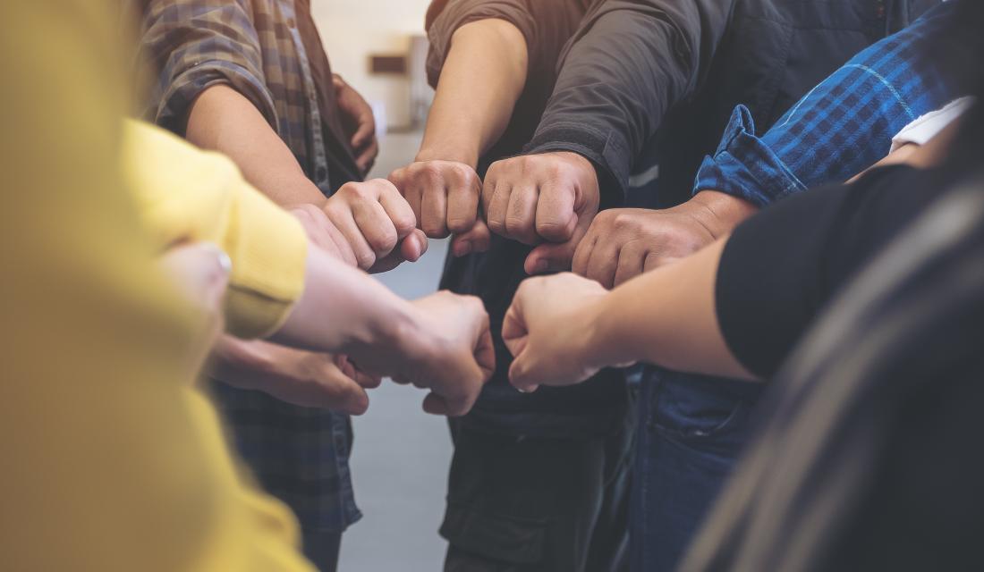 Gruppe von Menschen bilden einen Faustkreis