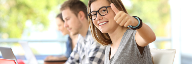 Studenten sitzen in einem Vorlesungsraum vor ihrem Laptop.