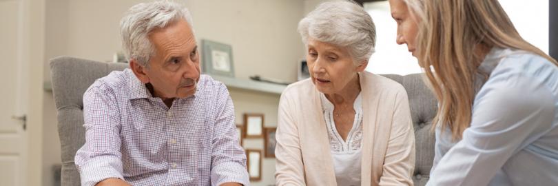 Zwei Senioren führen ein ernstes Gespräch mit einer jüngeren Frau