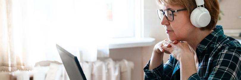 Frau hört mit Kopfhörern einem Vortrag zu