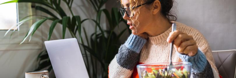 Frau isst Mittag an ihrem Schreibtisch