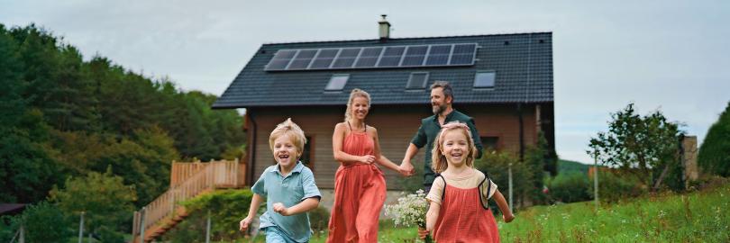 Familie auf einer Wiese vor Haus mit Photovoltaikanlage