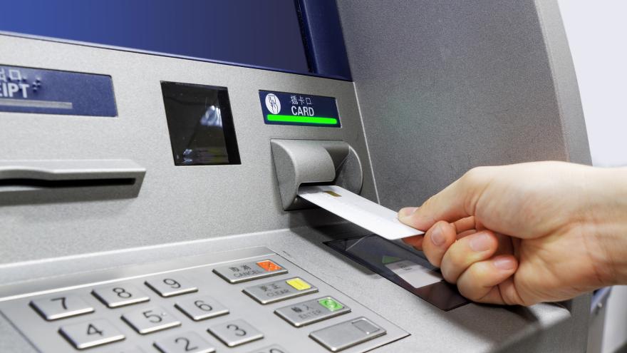 Ein Mensch steckt eine EC-Karte in einen Geldautomat