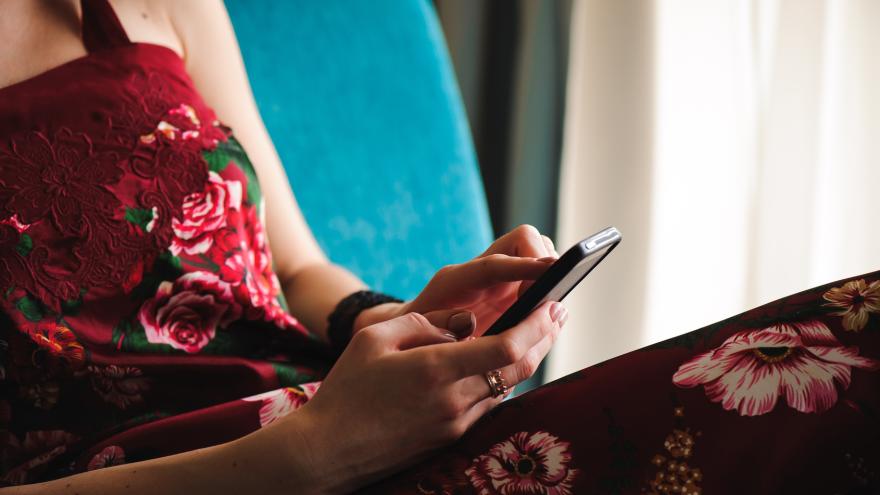 Eine Frau im Kleid tippt auf ihrem Smartphone.