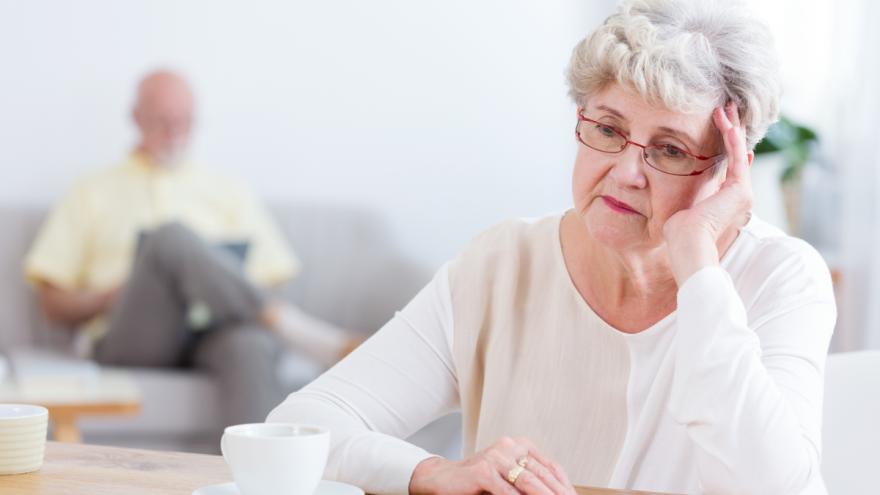Eine ältere Frau sitzt am Tisch und macht sich Sorgen.