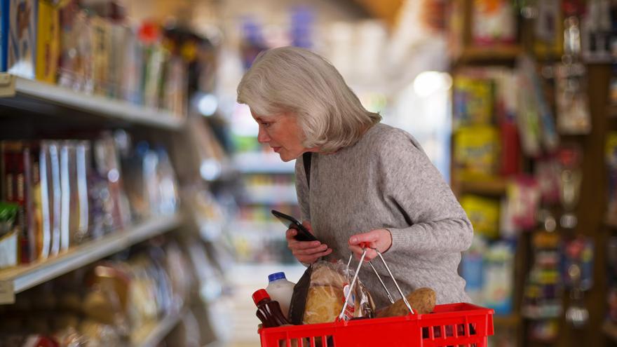 Eine Dame beim Einkauf mit dem roten Korb im Supermarkt
