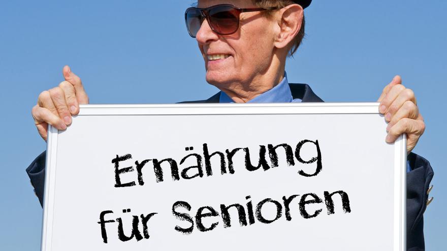 Ein älterer Herr hält den Schild "Ernährung für Senioren"
