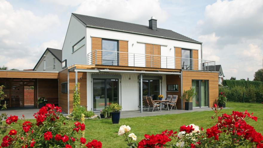 Haus mit überdachter Terrasse, rote Rosen im Vordergrund