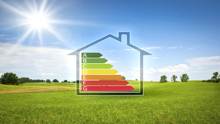 Haus mit Effizienzs-Skala vor grüner Landschaft mit Sonnenschein