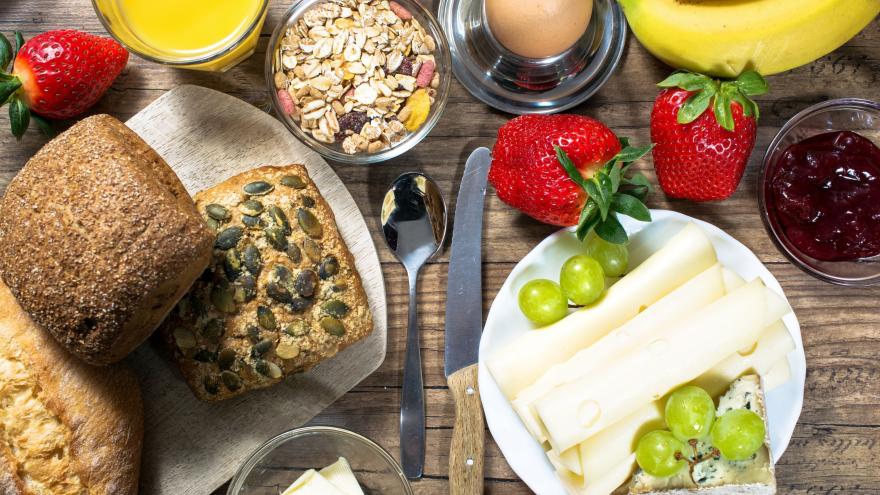 Ein Frühstückstisch mit Brötchen, Käse, Müsli und Obst