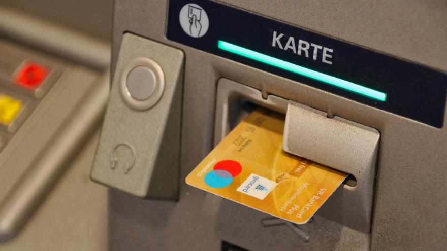 Eine Bankkarte steckt im Schlitz eines Geldautomaten