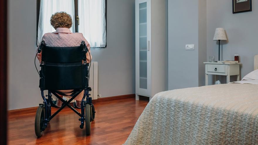 Seniorin im Rollstuhl in einem Pflegezimmer von hinten fotografiert