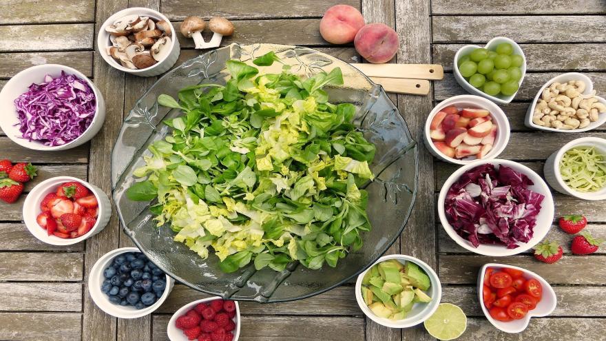 Eine große Schüssel mit Salat steht in der Mitte, viele kleine Schalen mit Früchten und Gemüse drumherum