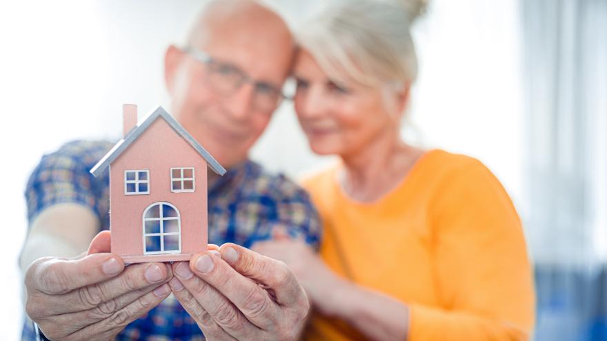 Älteres Ehepaar halten ein kleines Haus in den Händen