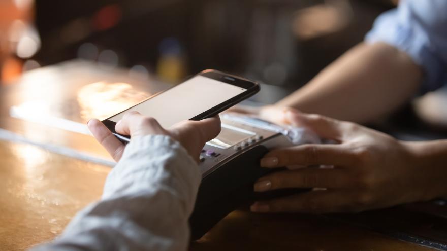 Mann hält Handy auf Lesegerät um zu bezahlen