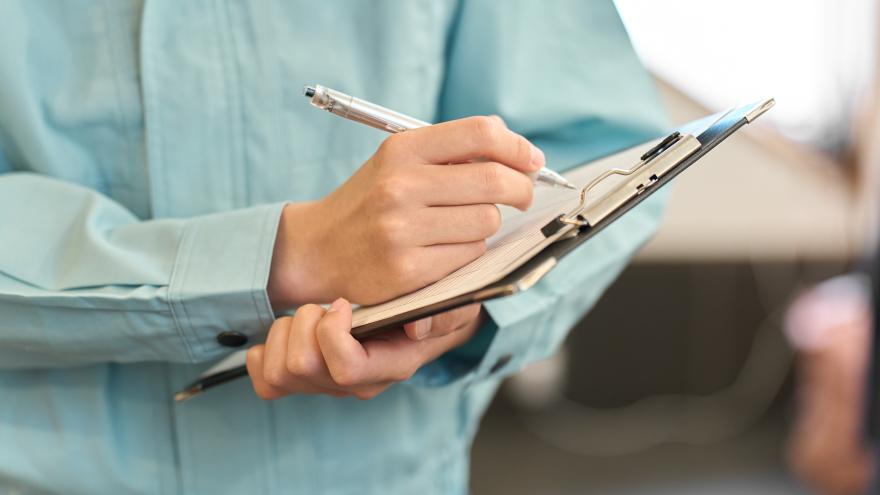 Jemand schreibt auf ein Klemmbrett