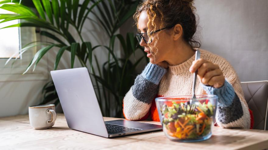 Frau isst Mittag an ihrem Schreibtisch