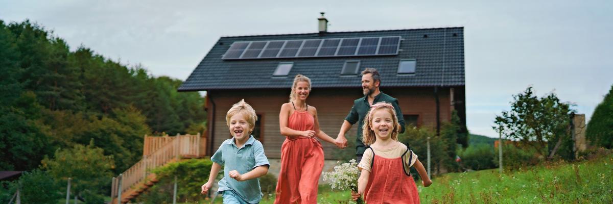 Familie auf einer Wiese vor Haus mit Photovoltaikanlage