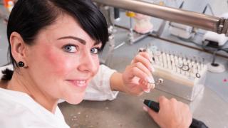 Zahntechnikerin im Dentallabor im Ausland stellt Zahnersatz her, sie bearbeitet eine Teilprothese für die Zähne.