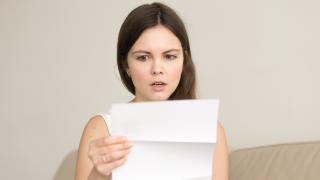 Frau liest erschrocken eine Mahnung.