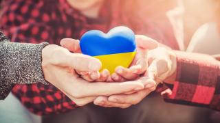 Hände halten ein Herz in den ukrainischen Farben blau und gelb