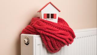 Heizung mit Schal und Miniaturhaus