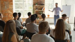 Mannspricht vor großer Gruppe zu einem Thema