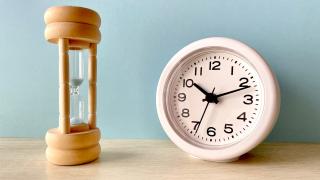 Sanduhr steht neben einer Uhr