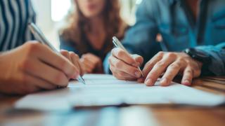 Zwei Menschen unterschreiben ein Dokument