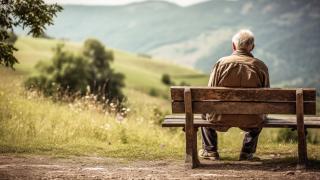 Mann sitzt auf Bank und schaut in die Natur