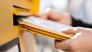Hände, die Briefe in einen Briefkasten werfen