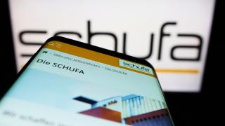 Smartphone mit Schufa-Homepage vor Schufa Logo