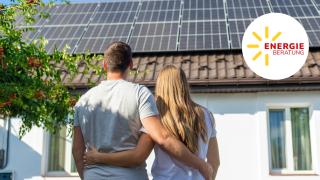 Junge Paar schaut auf ein Hausdach mit Photovoltaik