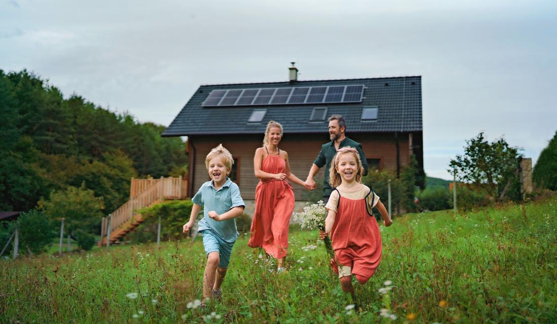 Familie auf einer Wiese vor Haus mit Photovoltaikanlage