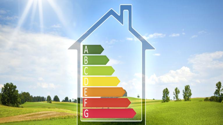 Haus mit Effizienzs-Skala vor grüner Landschaft mit Sonnenschein