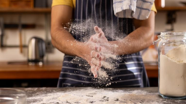 Mann verteilt Mehl auf Arbeitsfläche